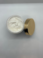 Jar of body butter with a gold lid on a light gray background