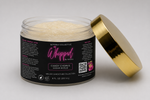 An open jar of Setoria Collective Whipped by Setoria Candy Chorus Sugar Scrub, featuring a black label with pink and white text and a metallic gold lid, set against a neutral gray background. 